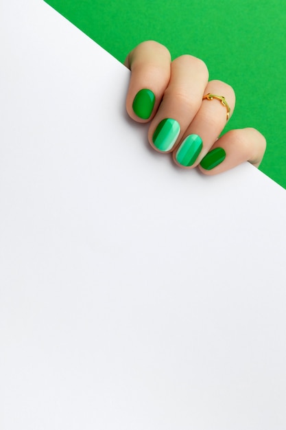 Womans hands with trendy green manicure holding postcard