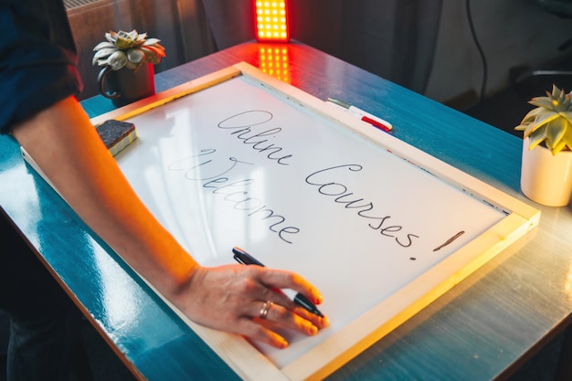 Photo womans hands writing welcome to online courses on white board standing at home coronavirus school sc...