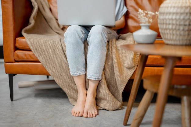 Womans legs on the floor while she working with laptop and sitting on sofa  high quality photo