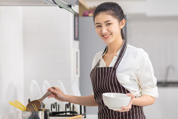 女性は朝食を作っており、アジアの女性は台所で朝食を作っています。