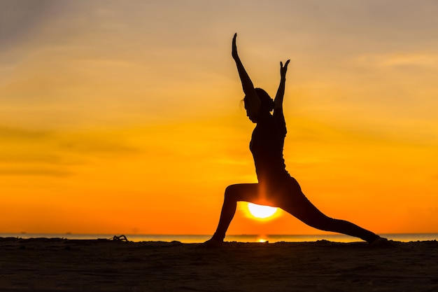 Women are exercising by doing yoga near the sea.