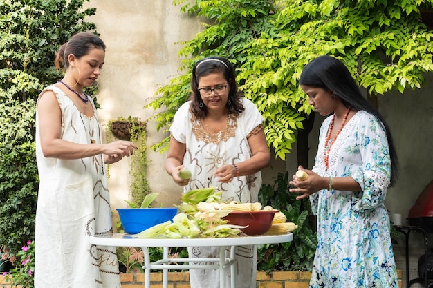 Women are peeling corn husks on a table at home