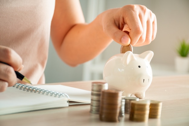 Women are putting coins in a piggy bank for a business that grows for profit and saving money for the future. planning for retirement concept