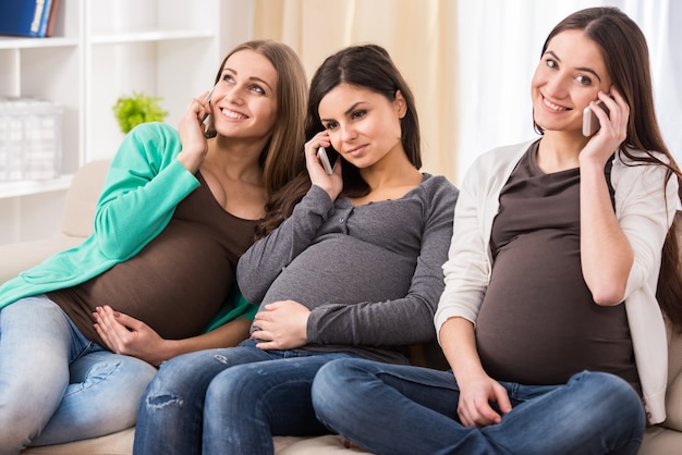 Photo women are talking by phone while sitting on the couch.