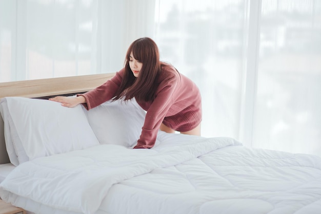 Women arrange sheets on the bed in the room.