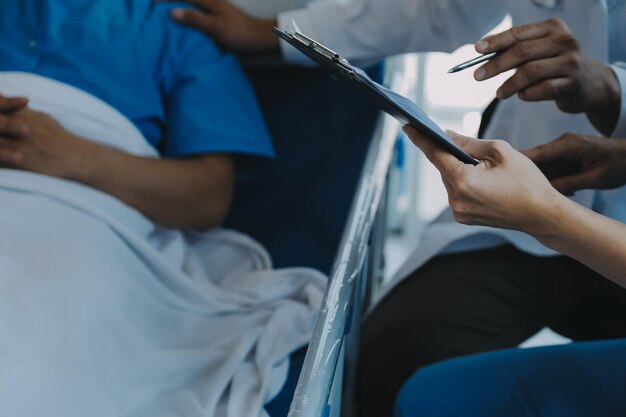 아시아 여성 의사들은 환자의 손을 잡고 격려하고 의료 조언을 제공하면서 침대에서 환자의 건강을 확인합니다.