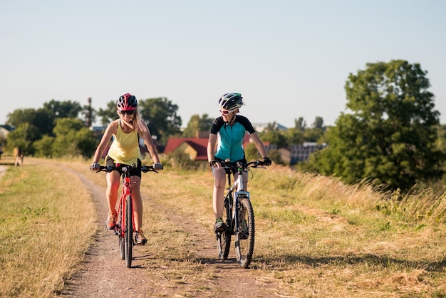 Women on bike riding by the lake shore outdoors at the park