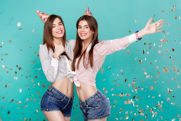 Donne in cappello di compleanno e coriandoli su sfondo blu