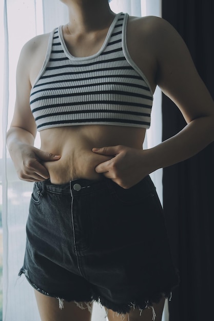 Foto donne pancia grassa obese donna mano che tiene eccessiva pancia grasso dieta stile di vita concetto per ridurre la pancia e formare muscoli dello stomaco sani