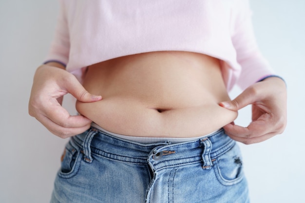 Women body fat belly. obese woman hand holding excessive belly fat. diet lifestyle concept to reduce belly