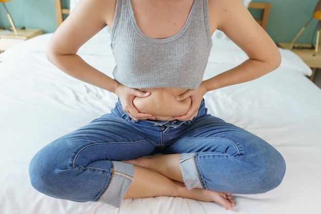 Foto pancia grassa del corpo delle donne. mano di donna obesa che tiene il grasso della pancia eccessivo.