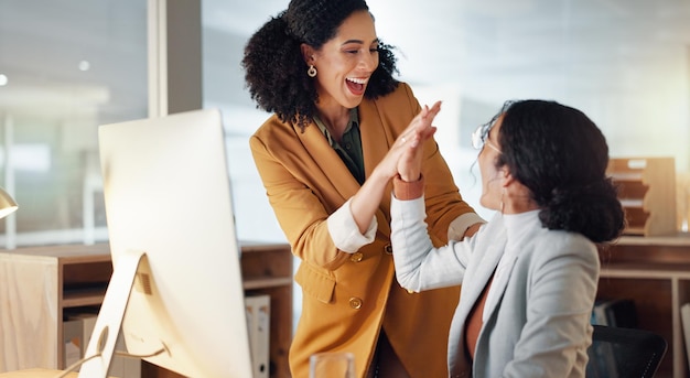 Foto donne d'affari e high five per il successo del lavoro di squadra supporto e collaborazione con il computer in ufficio celebrazione colleghi e felicità insieme con orgoglio o congratulazioni per il lavoro feedback