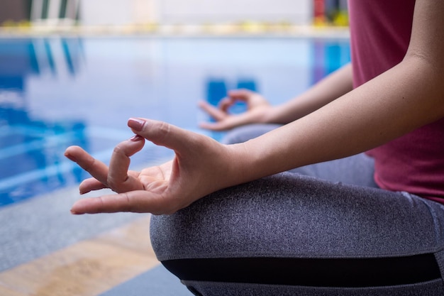 Women calmly meditate by the pool Woman doing yoga pose practicing peace of mind yoga concept
