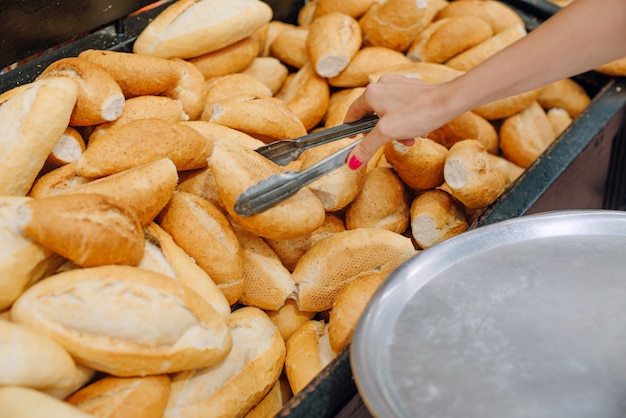 Women choosing bread at the supermarket. bun tongs and tray.