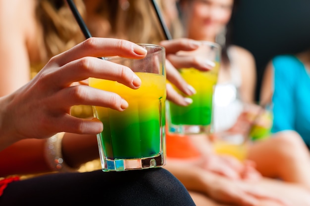 Photo women in club or disco drinking cocktails