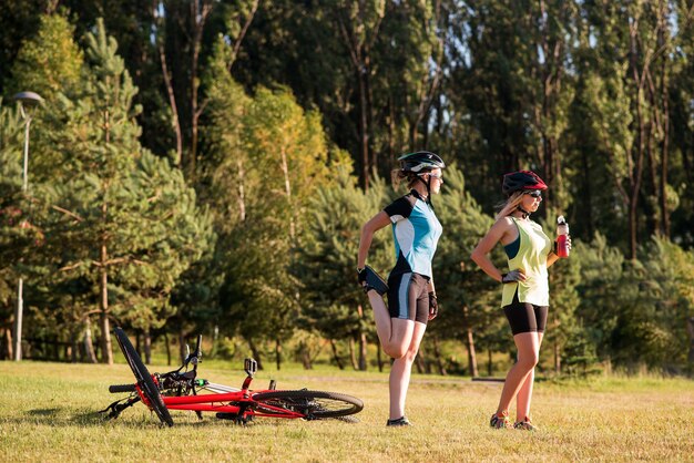 公園で屋外で自転車に乗った後に運動をしている女性サイクリスト