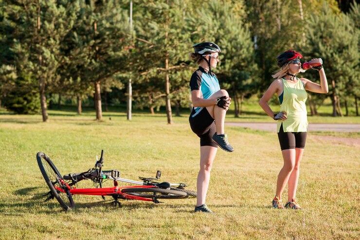 Photo women cyclist doing exercises after riding a bike outdoors in the park