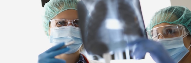 여성 의사는 사무실에 서서 폐 엑스레이를 보고