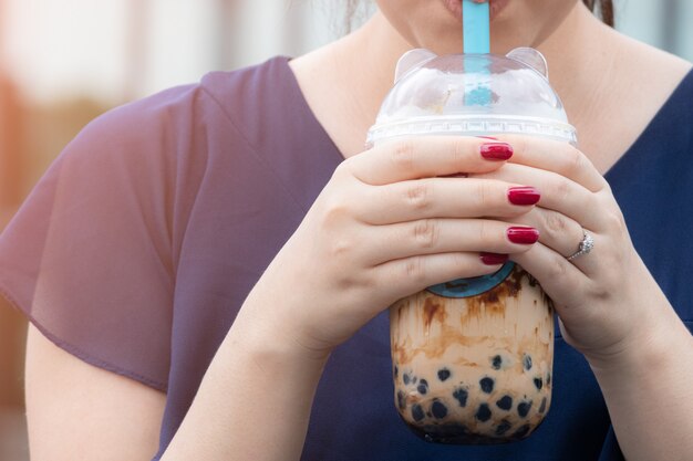 女性がストローでパールミルクティーを飲む