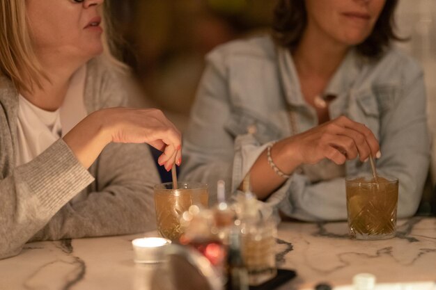 Women drinking alcoholic cocktails at the bar at the table