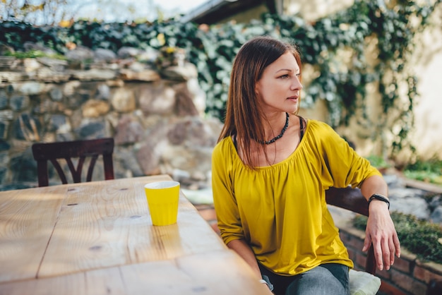 裏庭のパティオでコーヒーを飲む女性