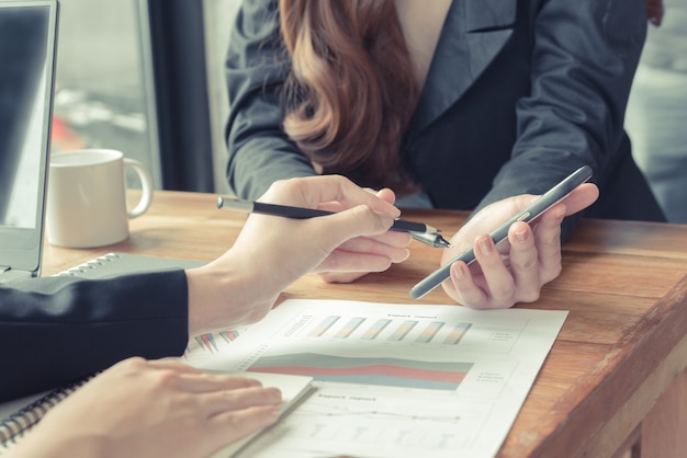 women duscuss use pens on cellphone in coffee shop