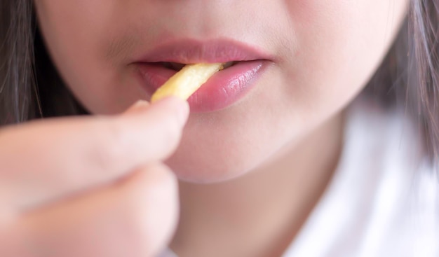 ぼんやりした背景でフライドポテトを食べている女性