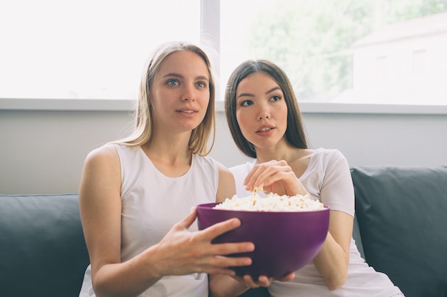 ポップコーンを食べてテレビを見ている女性