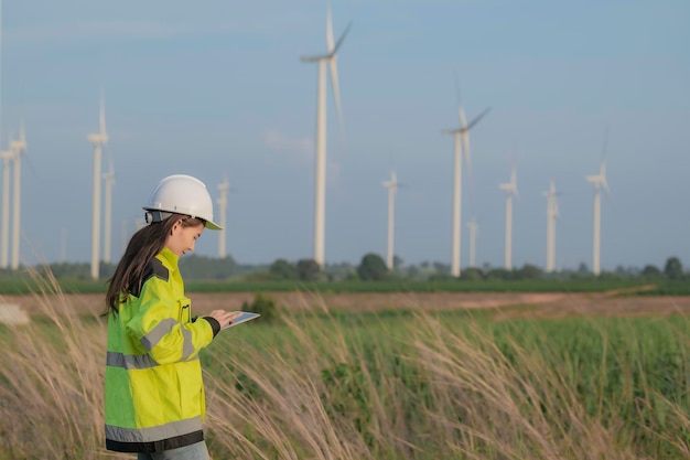 MountainThailandの人々の風力タービンファーム発電機ステーションで働いてレポートを保持している女性エンジニア