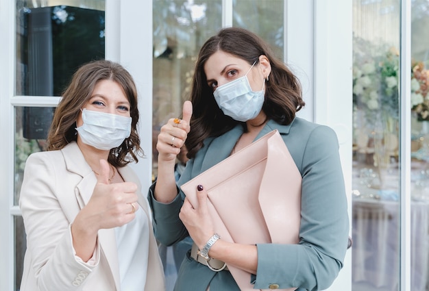 Women in face masks in suits at entrance to restaurant