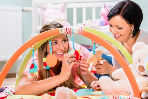 Le donne arredano la stanza del bambino preparando la barra di gioco per i lattanti