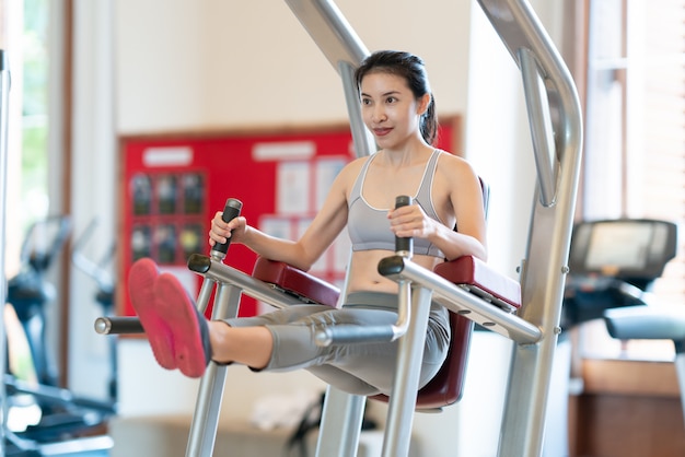 Women at the gym exercising on a machine.