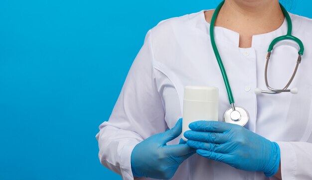 Women hand in blue sterile gloves holds a white plastic jar for pills