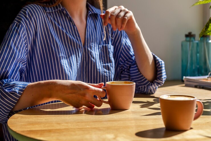 Women hand and coffee cup on wood desk in coffee shop or cafe close up