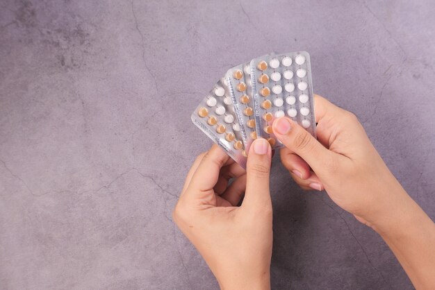 Women hand golding birth control pills on black background