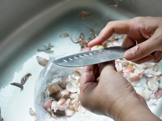 Photo women hand peeling garlic in the kitchen.