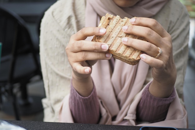 女性がハムチーズトマトのサンドイッチを手で選ぶ