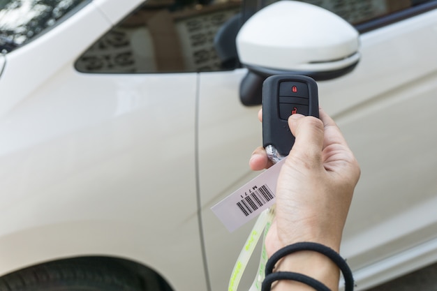 Women hand presses on the remote control car alarm systems. secure concept.