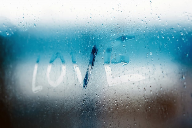 Women Hand's drawing LOVE word on glass window with water drop concept design