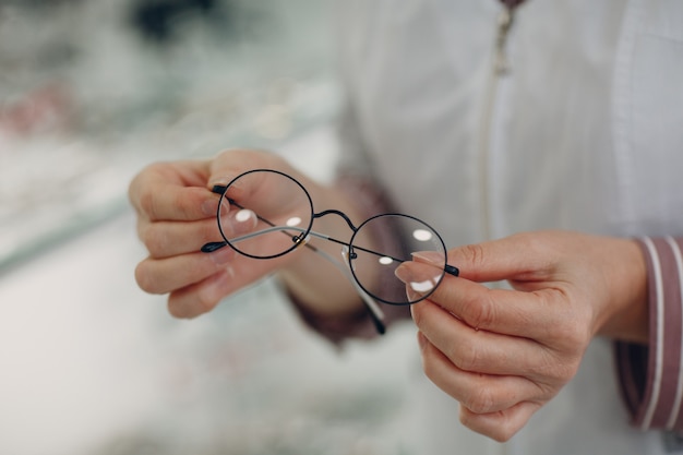 Women hand with trendy glasses lens. Eyeglasses transparent diopter.