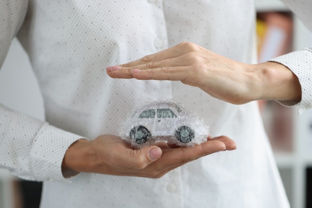 Photo women hands and car in packing bag as protection vehicle insurance concept