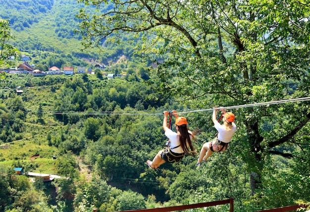 Foto donne appese a una corda nella foresta