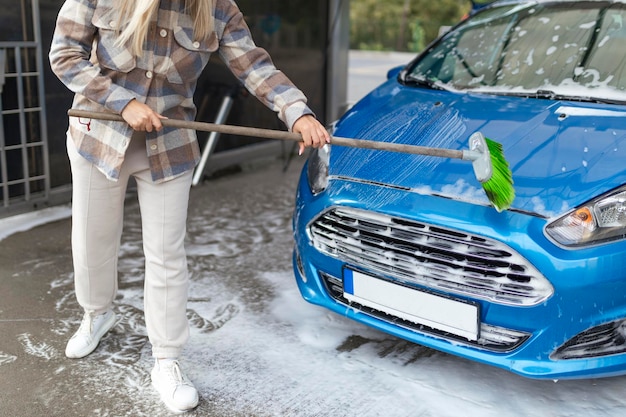 The women herself at the car wash washes the car with a brush