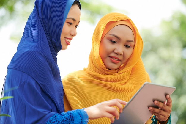 Women in hijabs with digital tablet