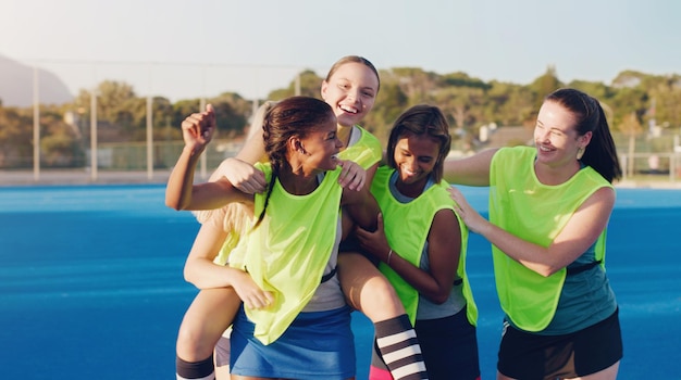 Women hockey group and celebration on field together for support solidarity and happy for fitness training or goals Sports teamwork friends and hug from with winning goal achievement or success