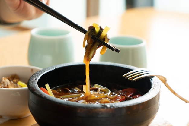 Women hold noodles with chopsticks