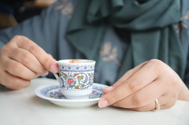 屋外のテーブルにトルコ コーヒーの aa カップを保持している女性