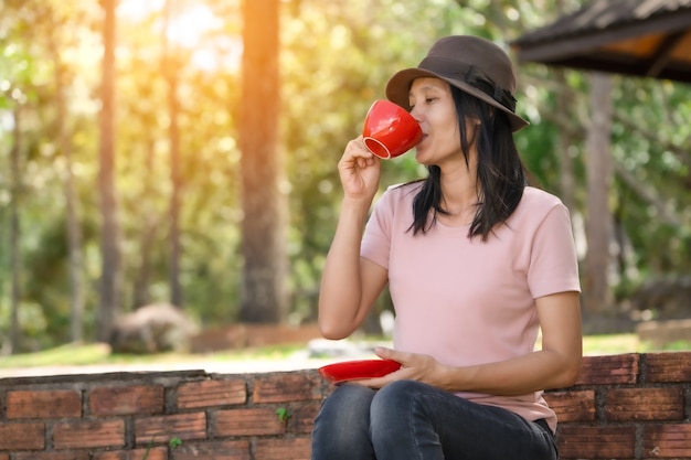 屋外の自然の中で朝にコーヒーを保持し、飲む女性