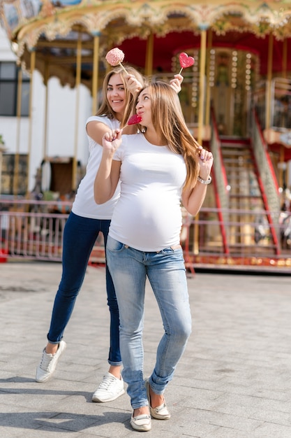 Women holding lollipops in the shape of a heart