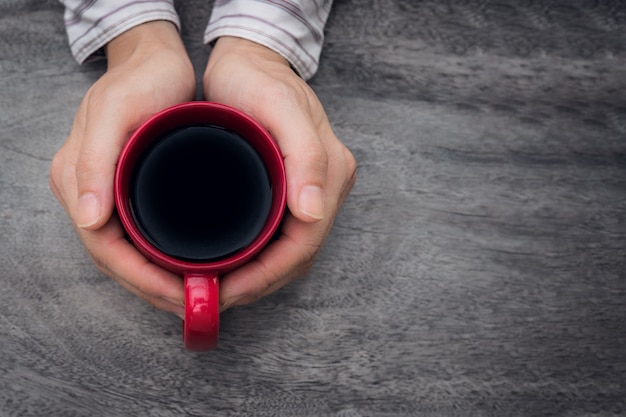 赤いコーヒーカップを手にしている女性。